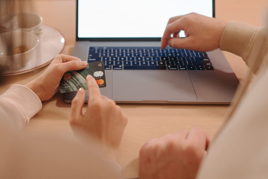 Online shopper holding a credit card and tablet with a sale offer, representing coupons, points, and final checkout costs.